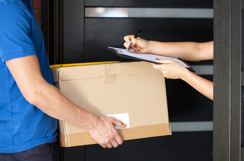 Delivery guy holding package while woman is signing documents-1
