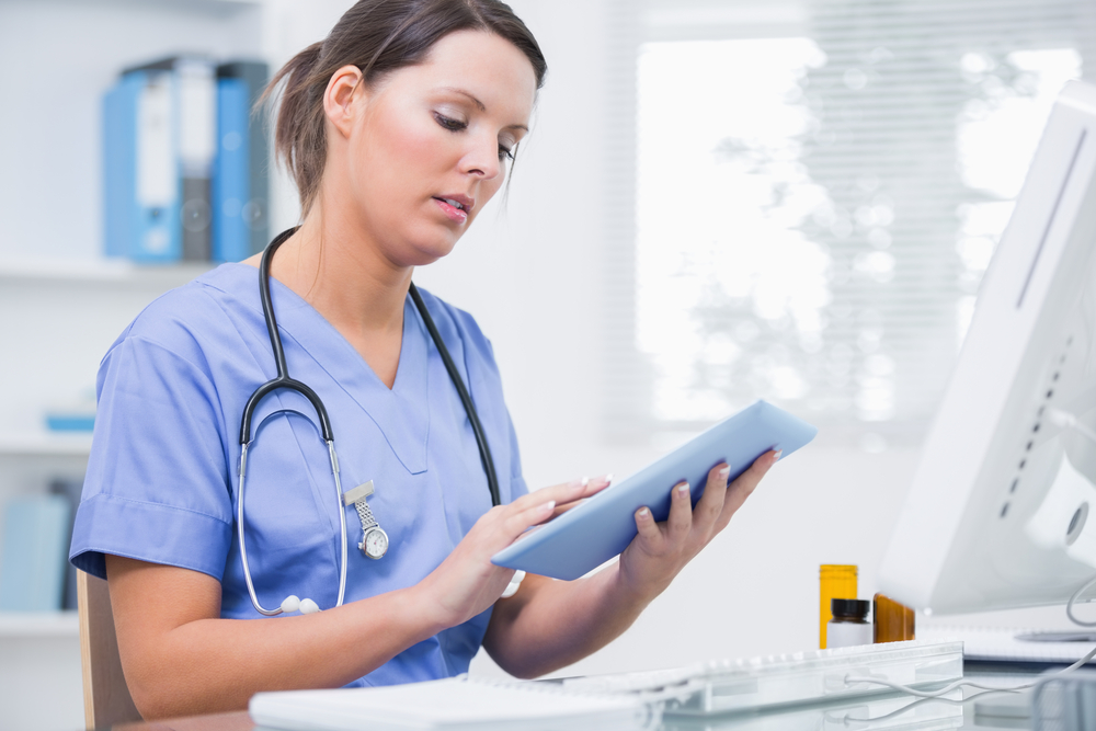 Nurse in hospital setting looks at tablet