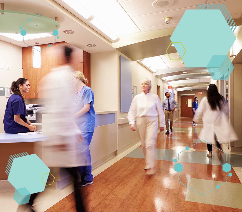 A busy hospital hallway with nurses and clinicians walking and talking