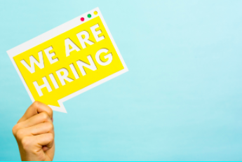 Person holding We Are Hiring sign